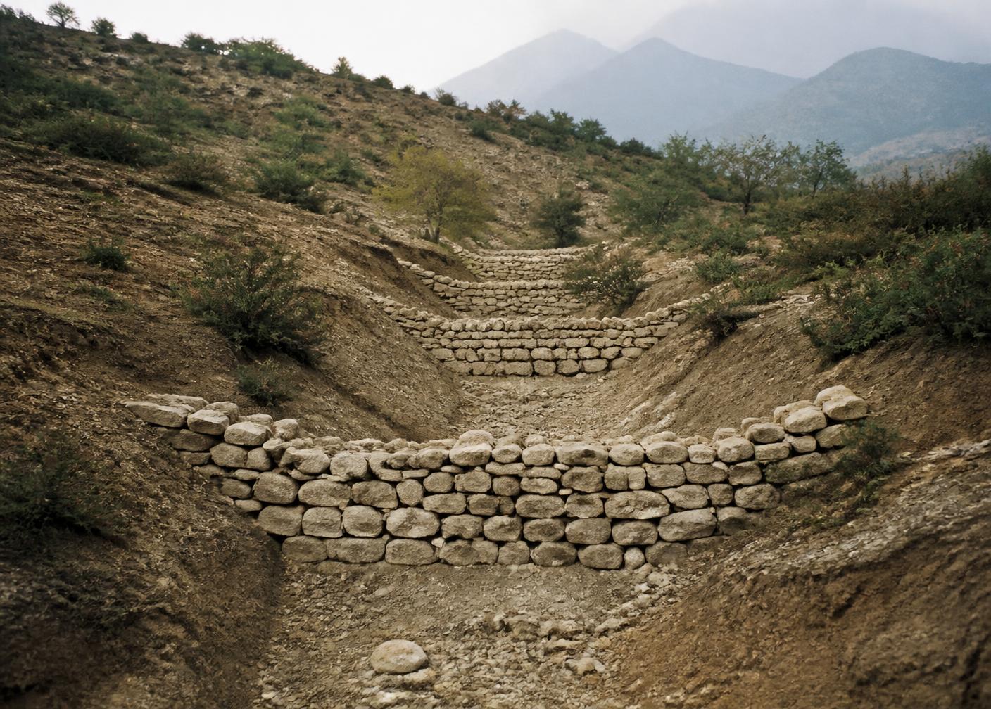 Dry-stone check dams built across an eroded gully